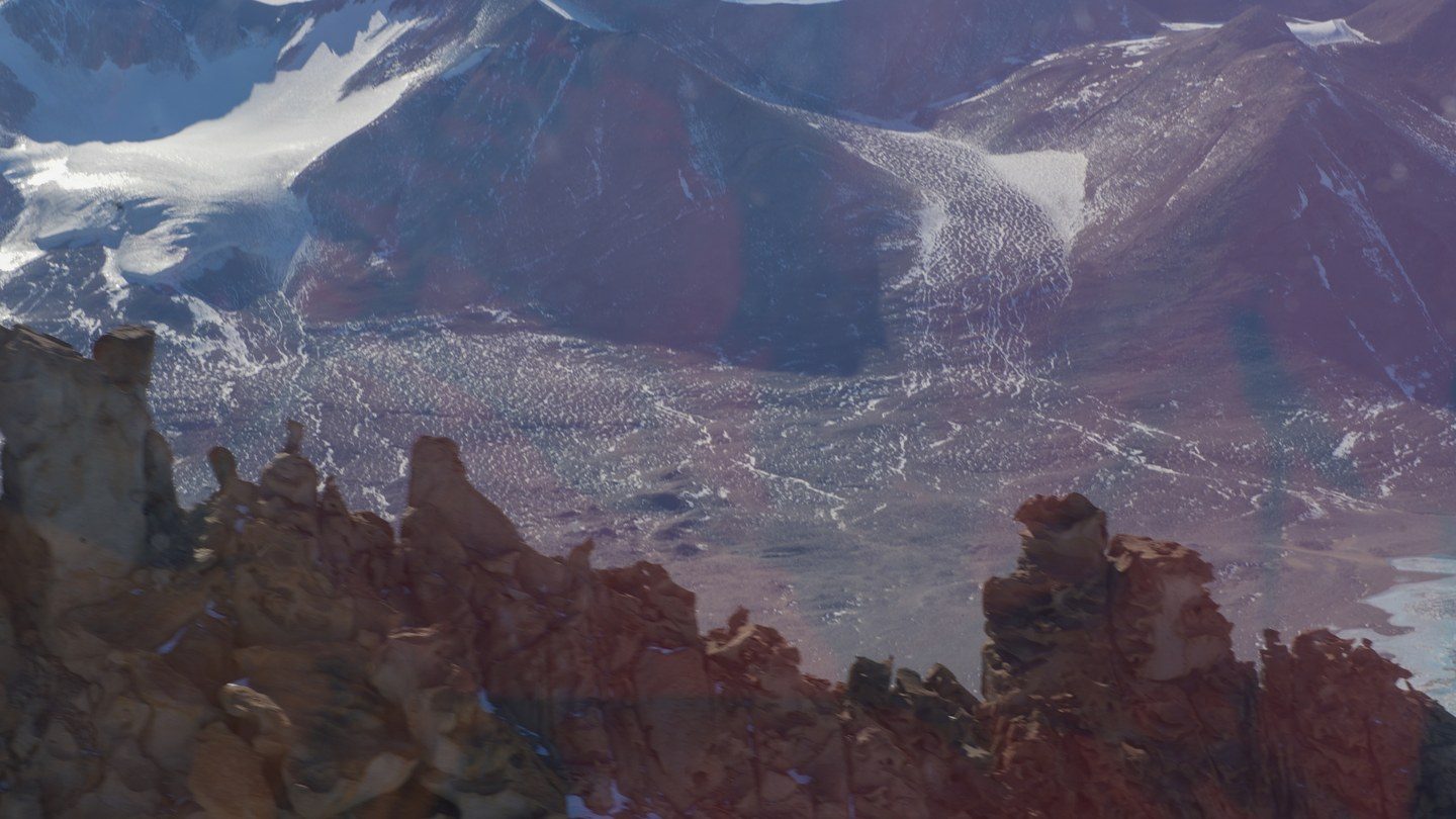 Bare, wind-scoured rock and gravel of Gargoyle Ridge in the ice-free McMurdo Dry Valleys, Antarctica, with sparse snow patches and a clear sky over the ridge line