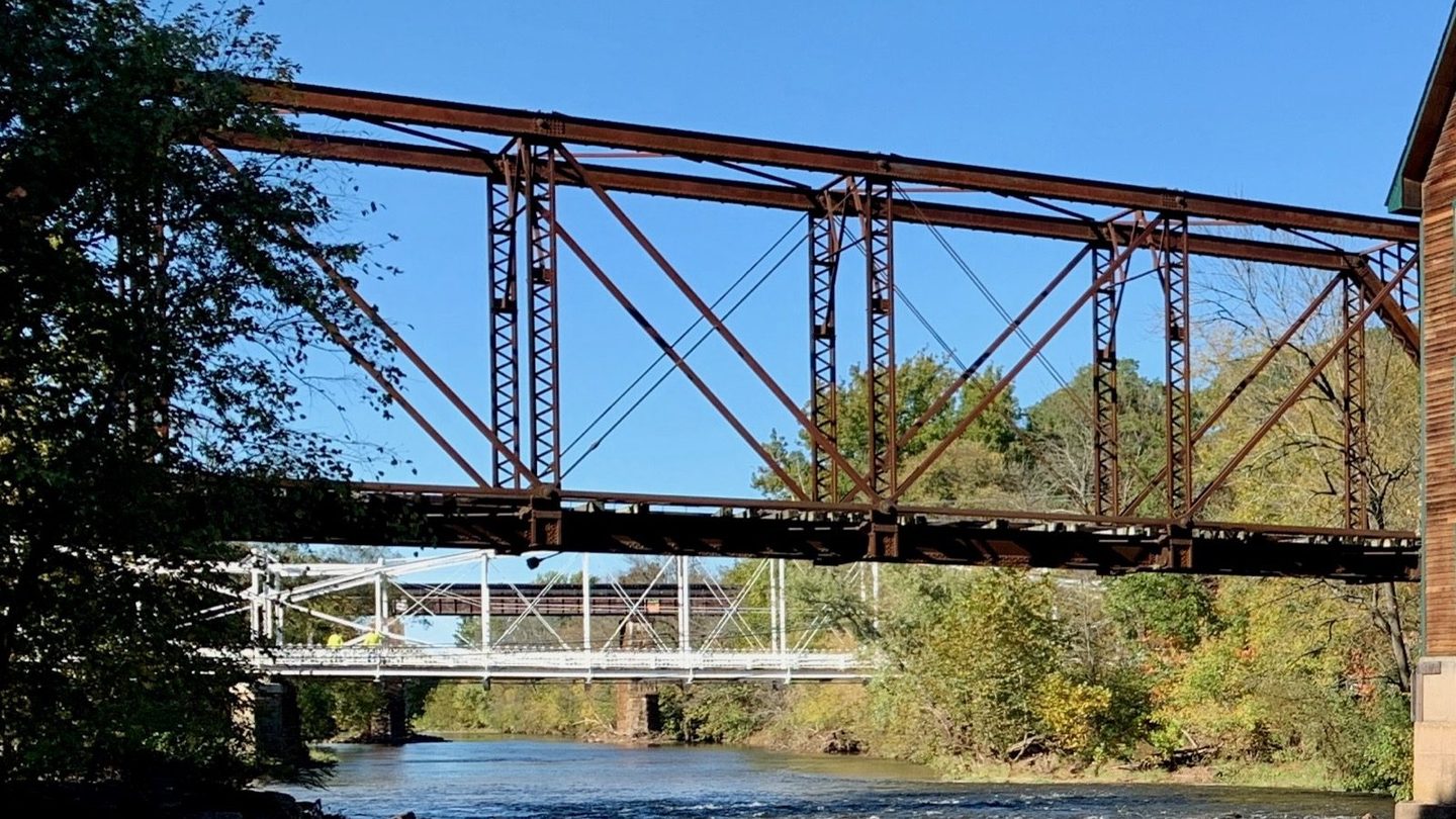 A steel through Pratt truss bridge, a former New Jersey Central Railroad crossing at Neshanic Station, showing the triangular web of diagonal and vertical members between the parallel top and bottom chords